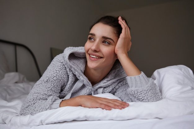 beautiful-young-brunette-brown-eyed-lady-leaning-her-head-raised-hand-looking-cheerfully-aside-with-charming-smile-lying-white-bed-linens-casual-clothes_295783-5050